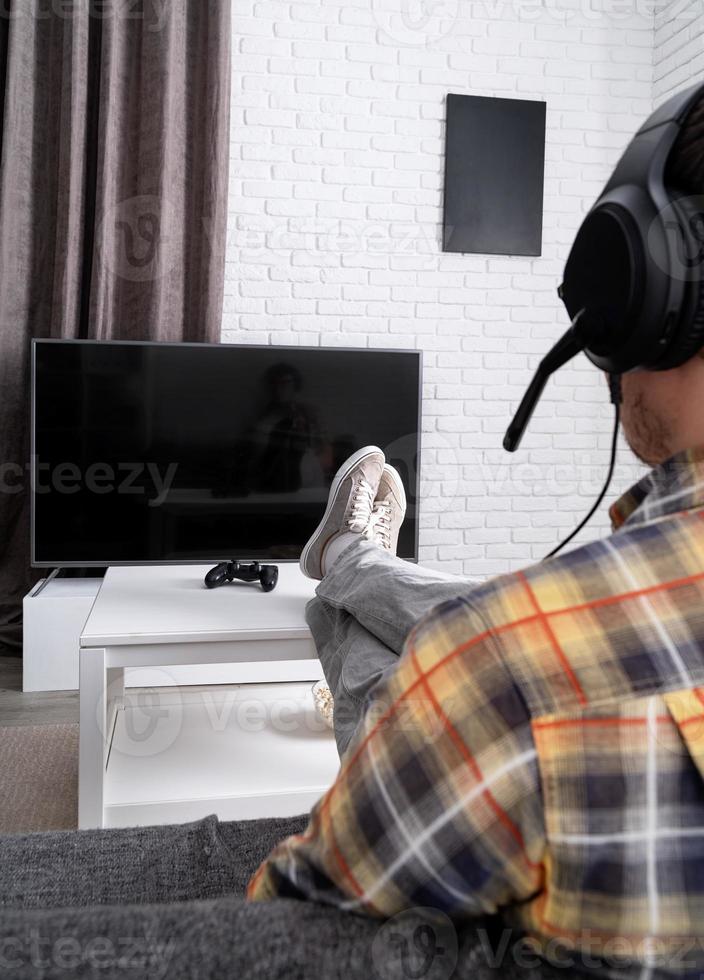 Rear view of a young man playing video games at home photo