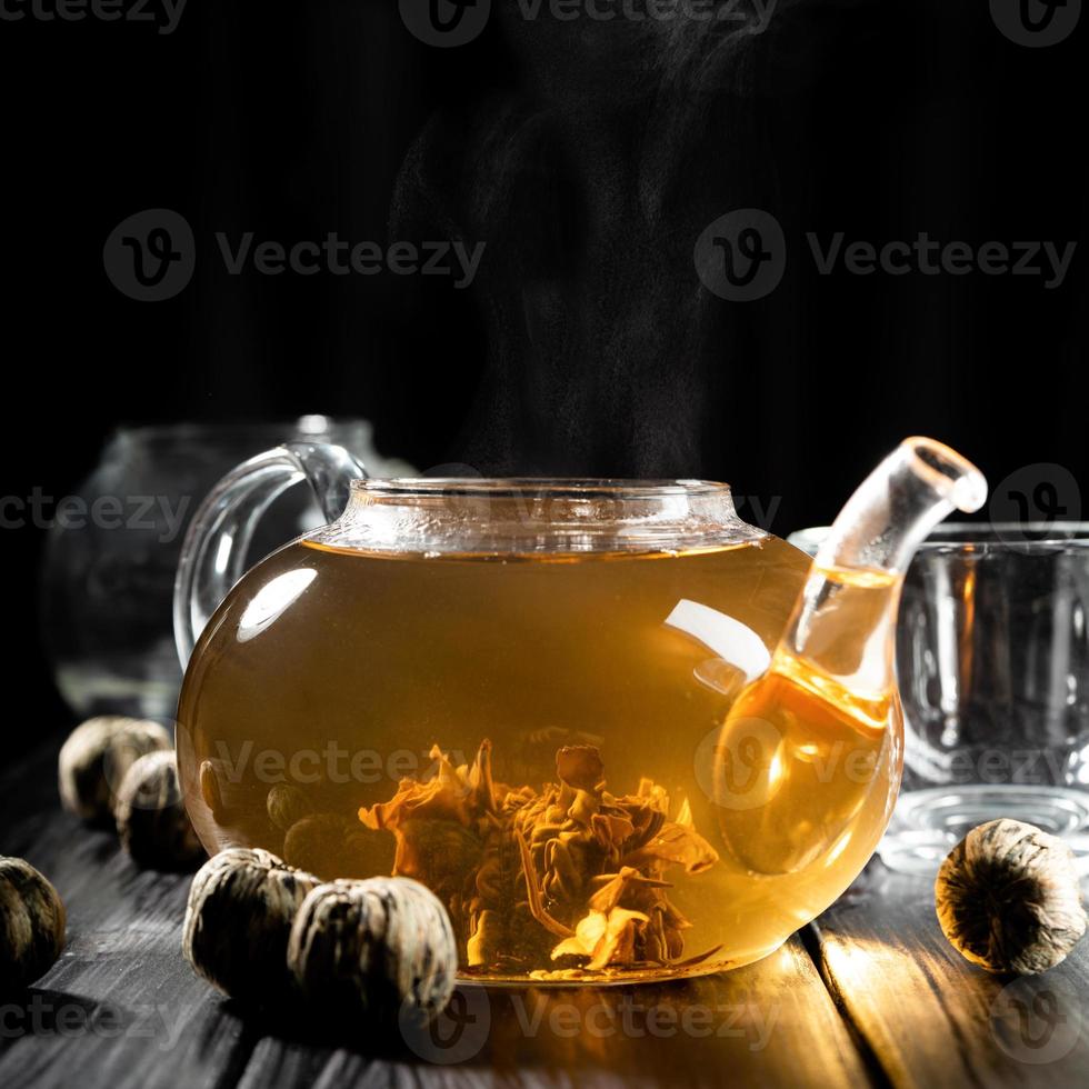 Hot water pouring into the glass teapot with chinese tea photo