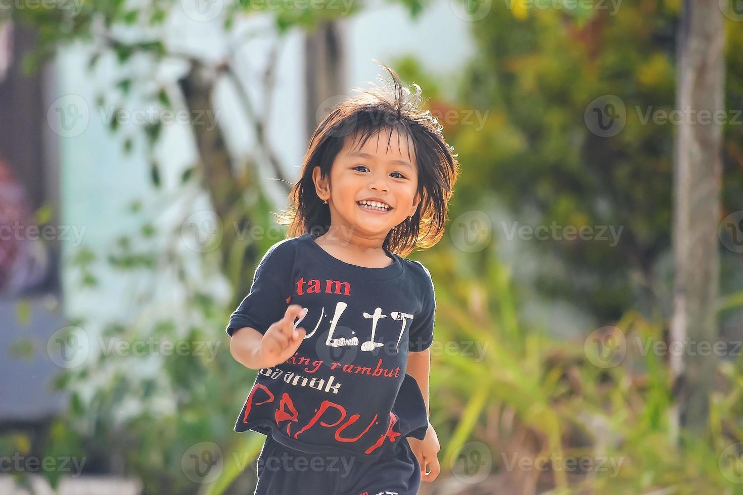 una niña se está divirtiendo y corriendo. una sonrisa sincera en el rostro de una niña malaya. foto