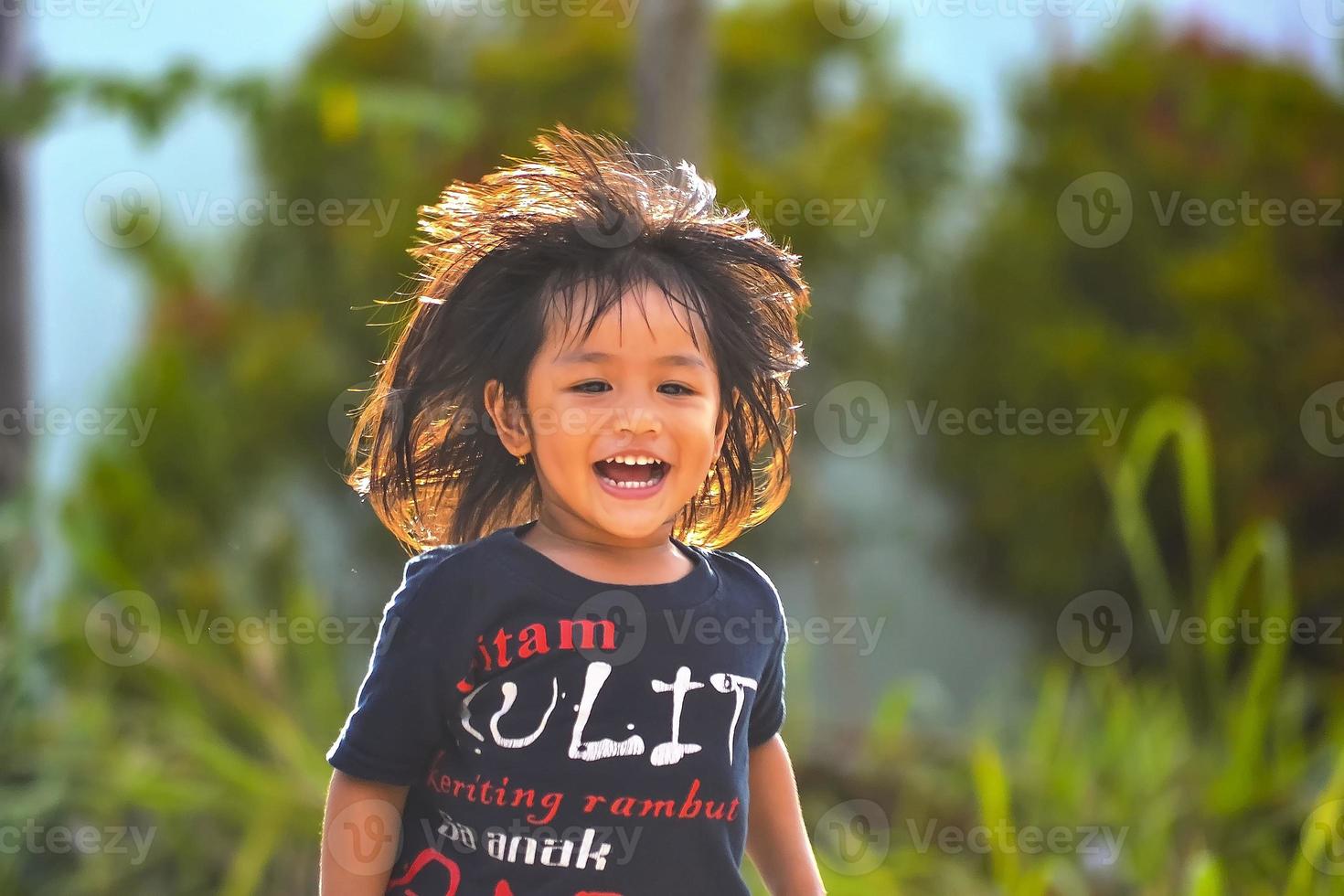 a little girl is having fun and running. A sincere smile on the face of a malay toddler girl. photo