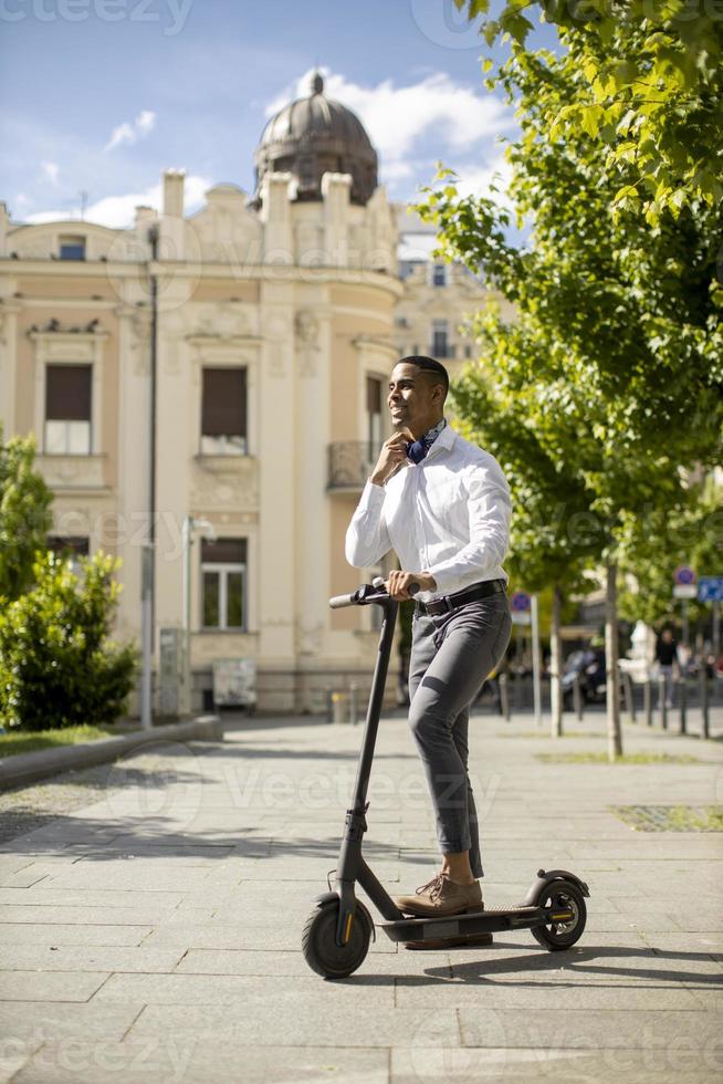 Joven afroamericano con scooter eléctrico en una calle foto