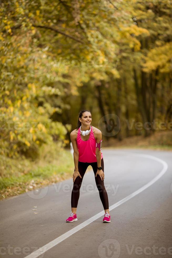 Mujer joven tiene un descanso durante el entrenamiento en el bosque de otoño foto