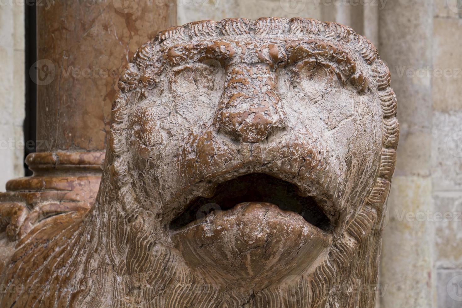 Escultura de león con rezar delante del Duomo de Módena, Italia foto