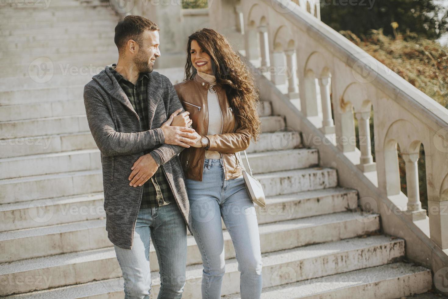 Young couple smiling and talking while strolling down outdoor stairs on autumn day photo