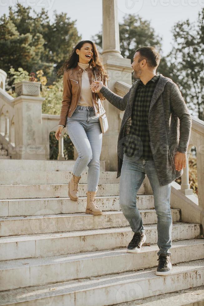 Young couple smiling and talking while strolling down outdoor stairs on autumn day photo