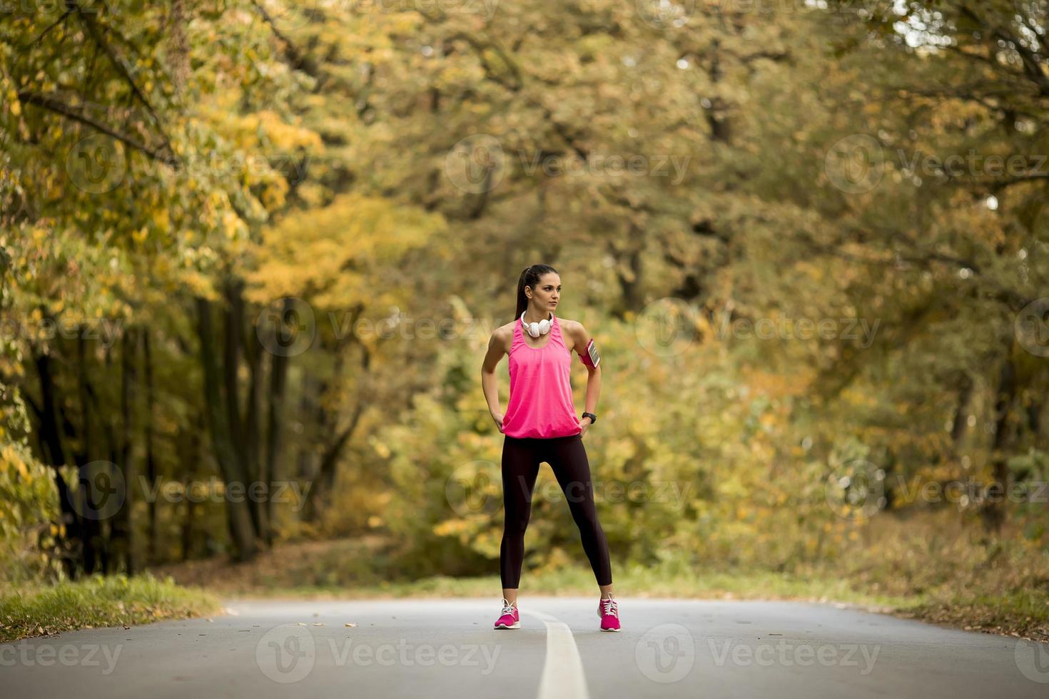 Mujer joven tiene un descanso durante el entrenamiento en el bosque de otoño foto