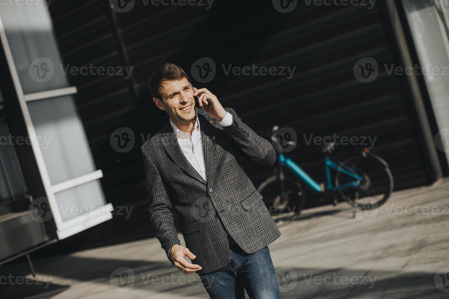 joven empresario alejándose de la bicicleta eléctrica y usando un teléfono móvil foto