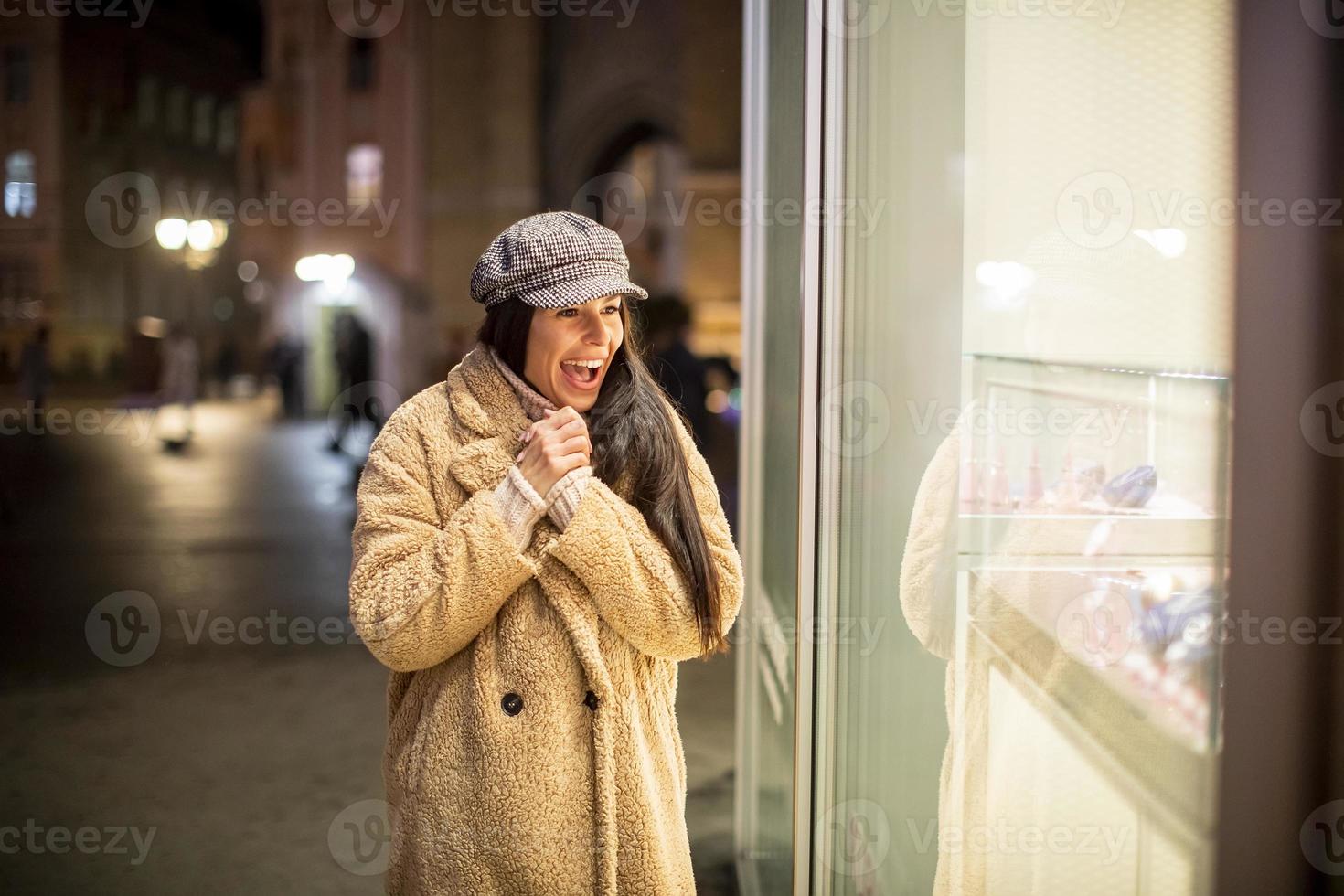 Beautiful young woman by the shop window at Christmas time photo
