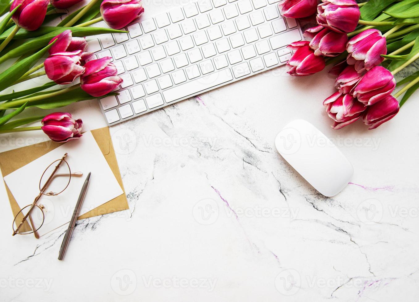 espacio de trabajo con teclado y tulipanes foto