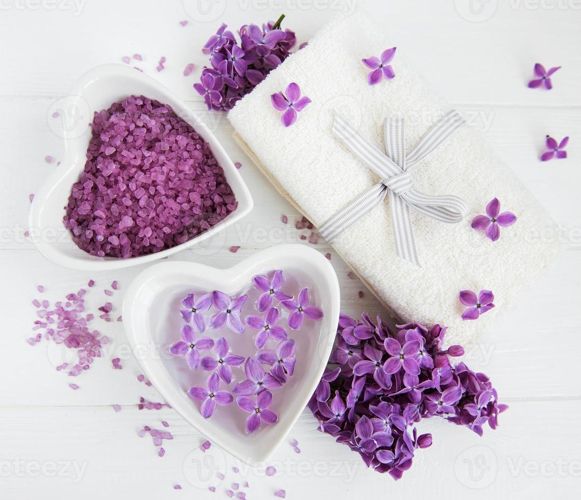 Toalla de spa y productos de masaje con flores lilas. foto