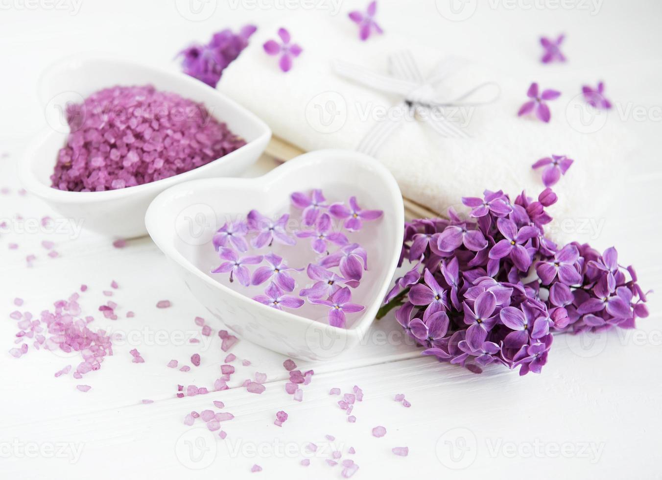 Toalla de spa y productos de masaje con flores lilas. foto