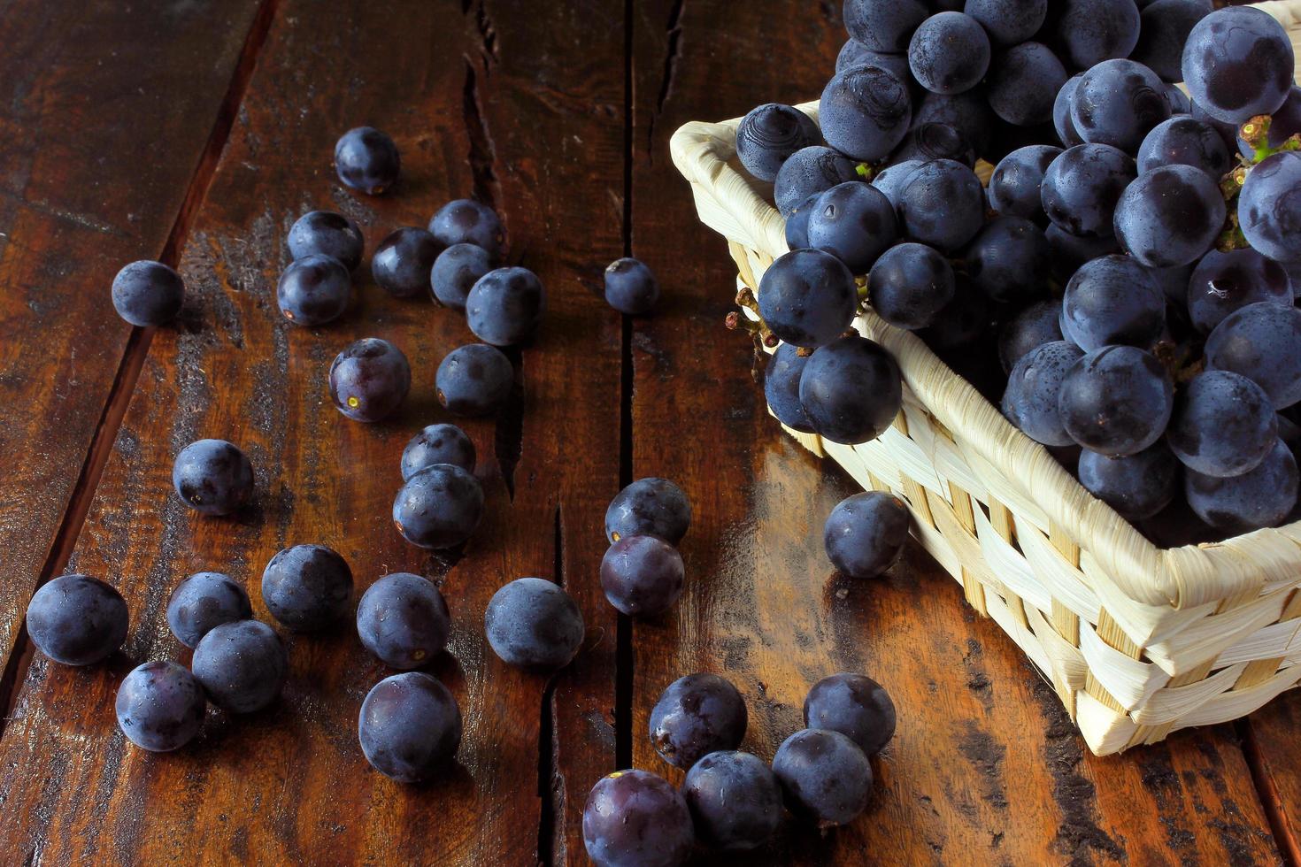 bunches of grapes, inside bamboo fiber basket on wooden table photo