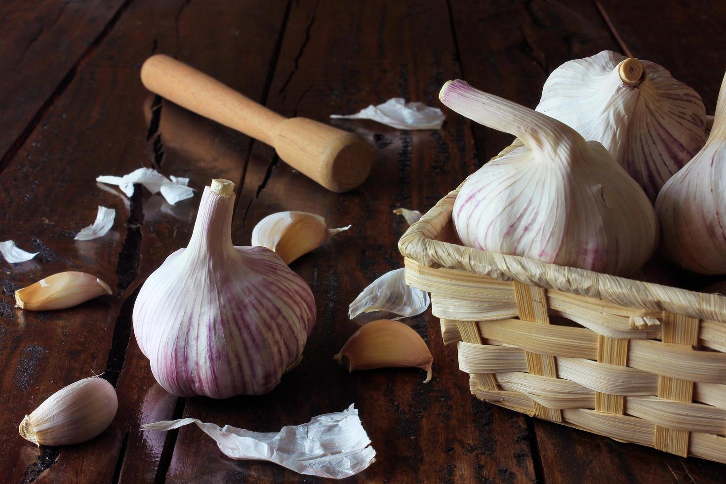 Garlic bulbs inside basket of straw, on rustic wooden table. Closeup garlic photo