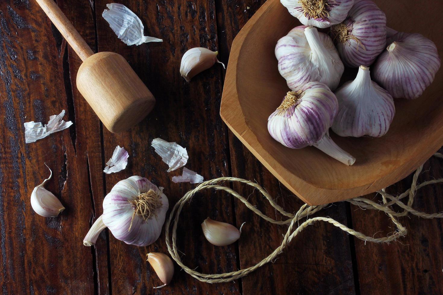 Garlic bulbs inside rustic wooden bowl on rustic wooden table. Closeup of garlic photo