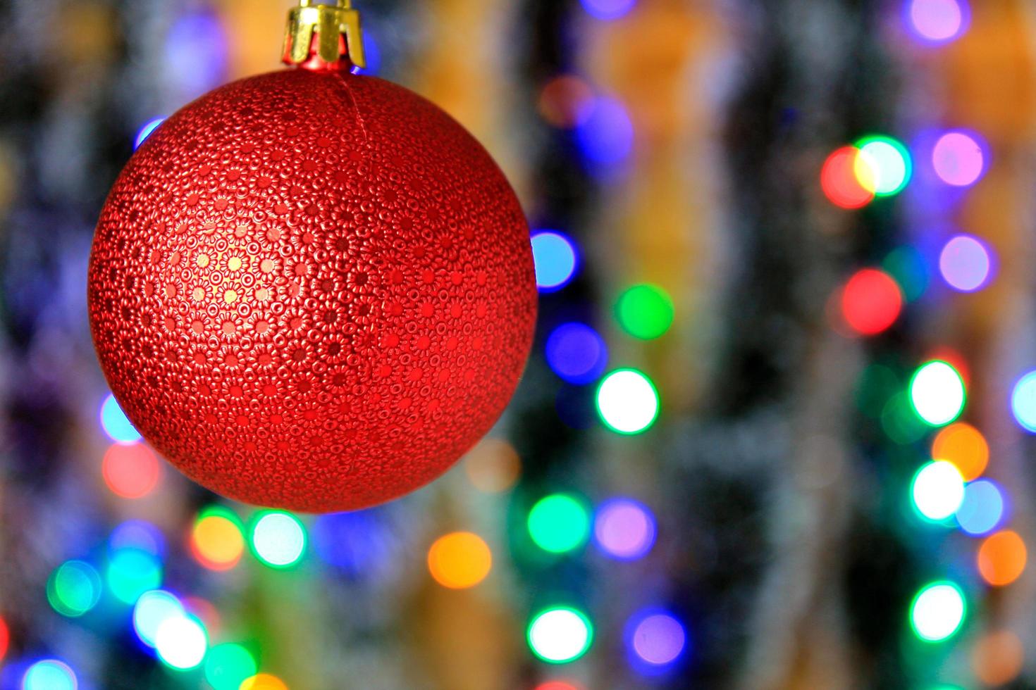 Bola colgante roja, decoración navideña con fondo de luces borrosas. foto