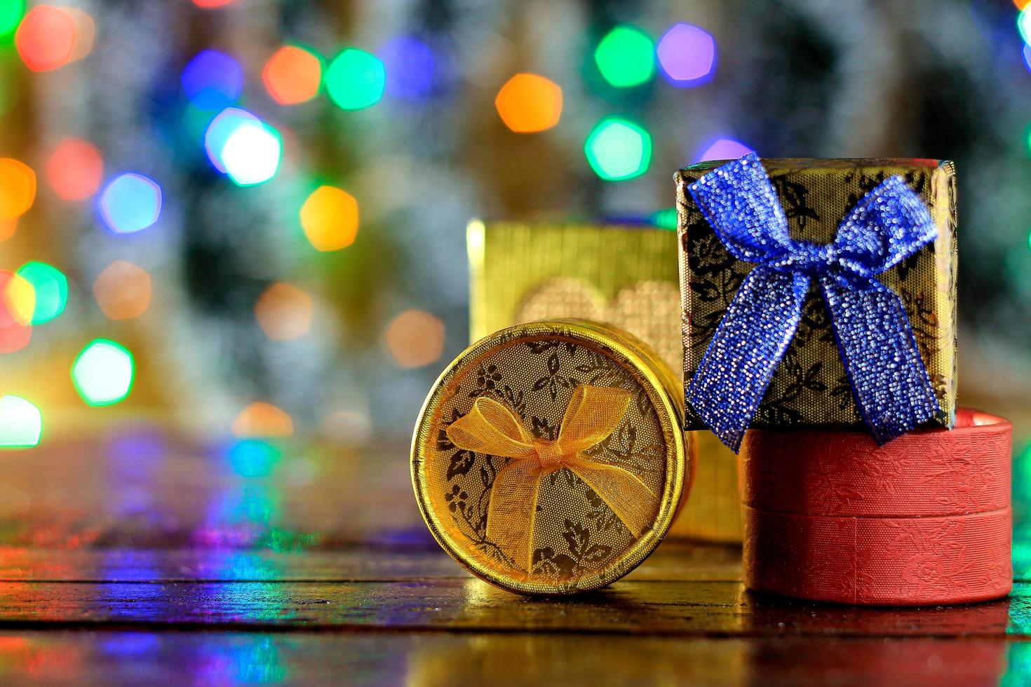 Cajas de regalo en la mesa de madera, decoración navideña, luces borrosas foto