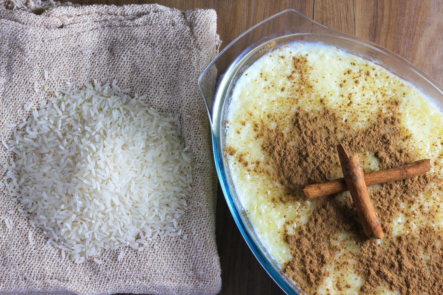 rice pudding with cinnamon in glass container on wooden table, rice over rustic bag photo