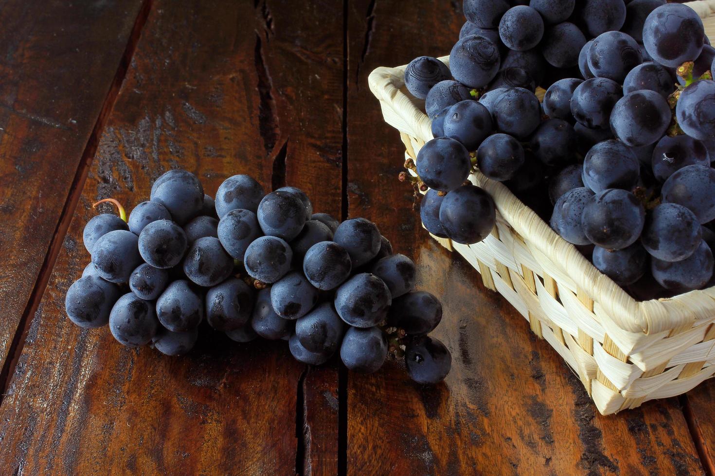 bunches of grapes, inside bamboo fiber basket on wooden table photo
