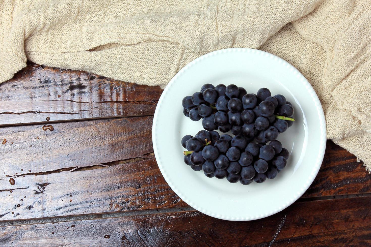 bunches of fresh grapes, inside ceramic dish, on rustic wooden table photo