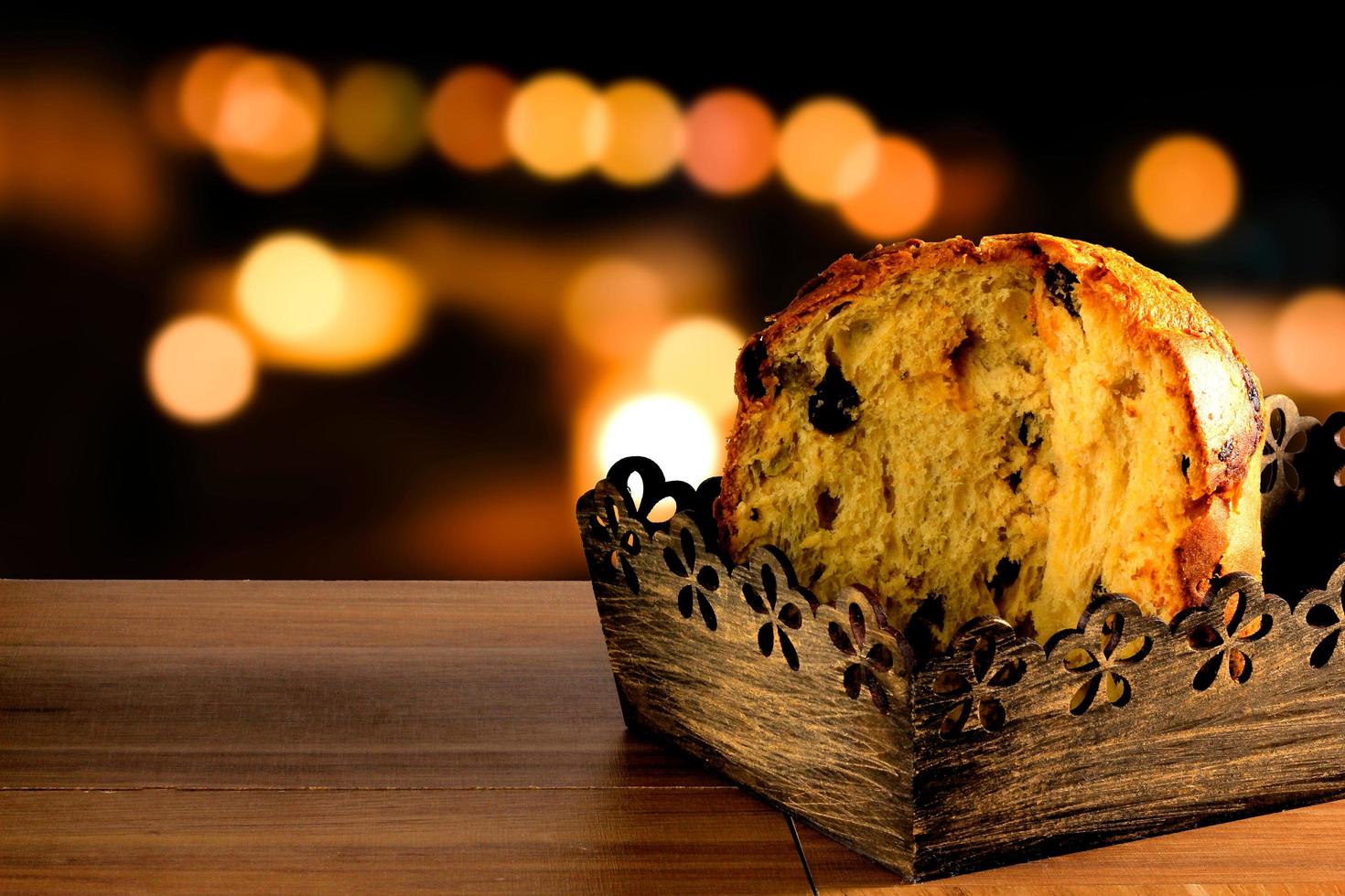 closeup panettone inside box on wooden table, bokeh background with lights photo