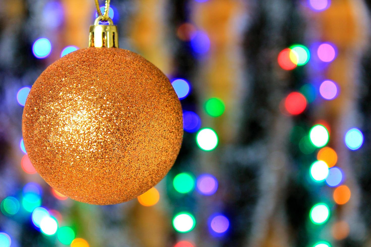 Golden hanging ball, christmas decoration with blurred lights background. photo