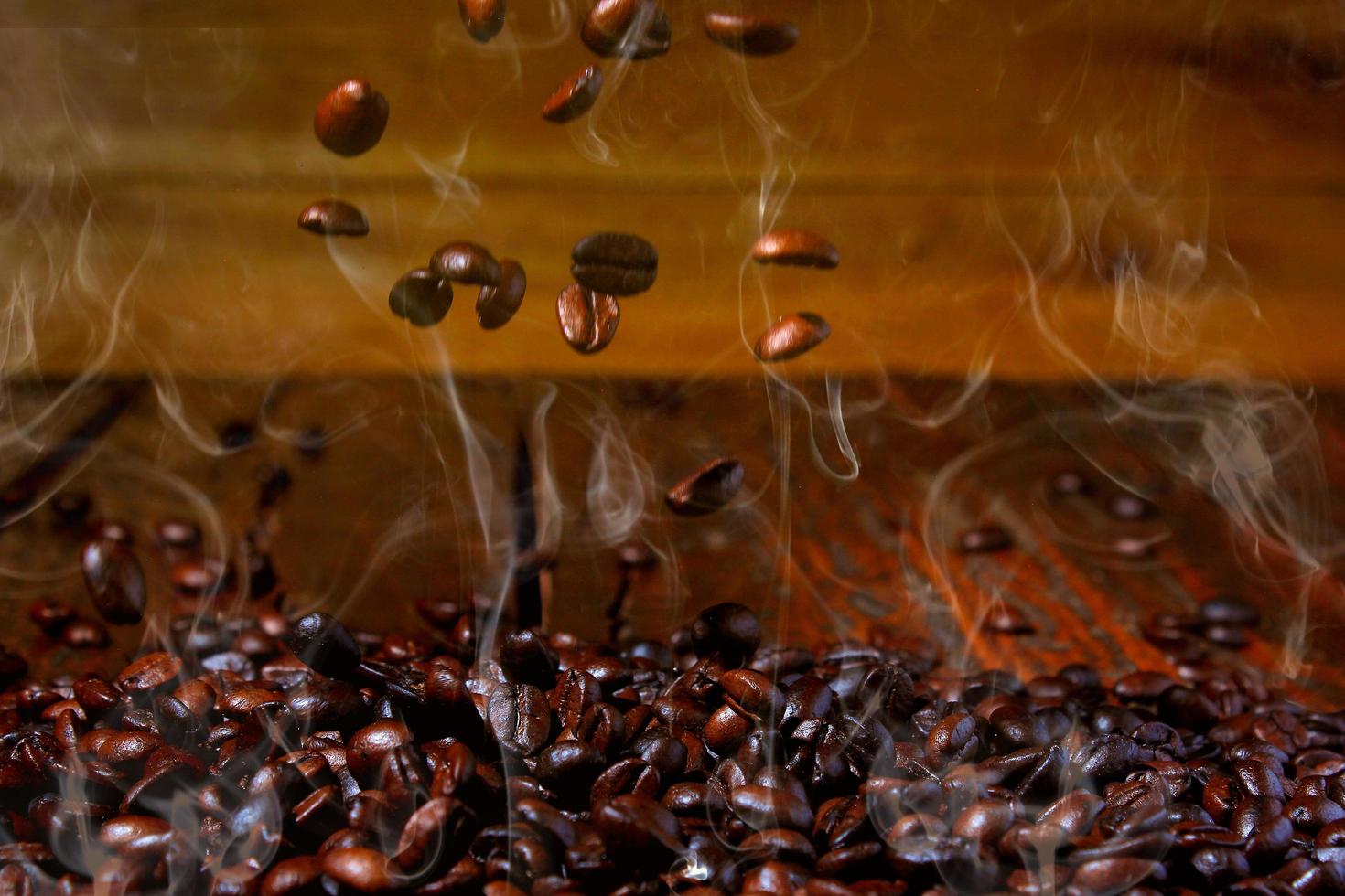 roasted coffee beans falling on stack, hot and smoky. Rustic wood background blurred photo