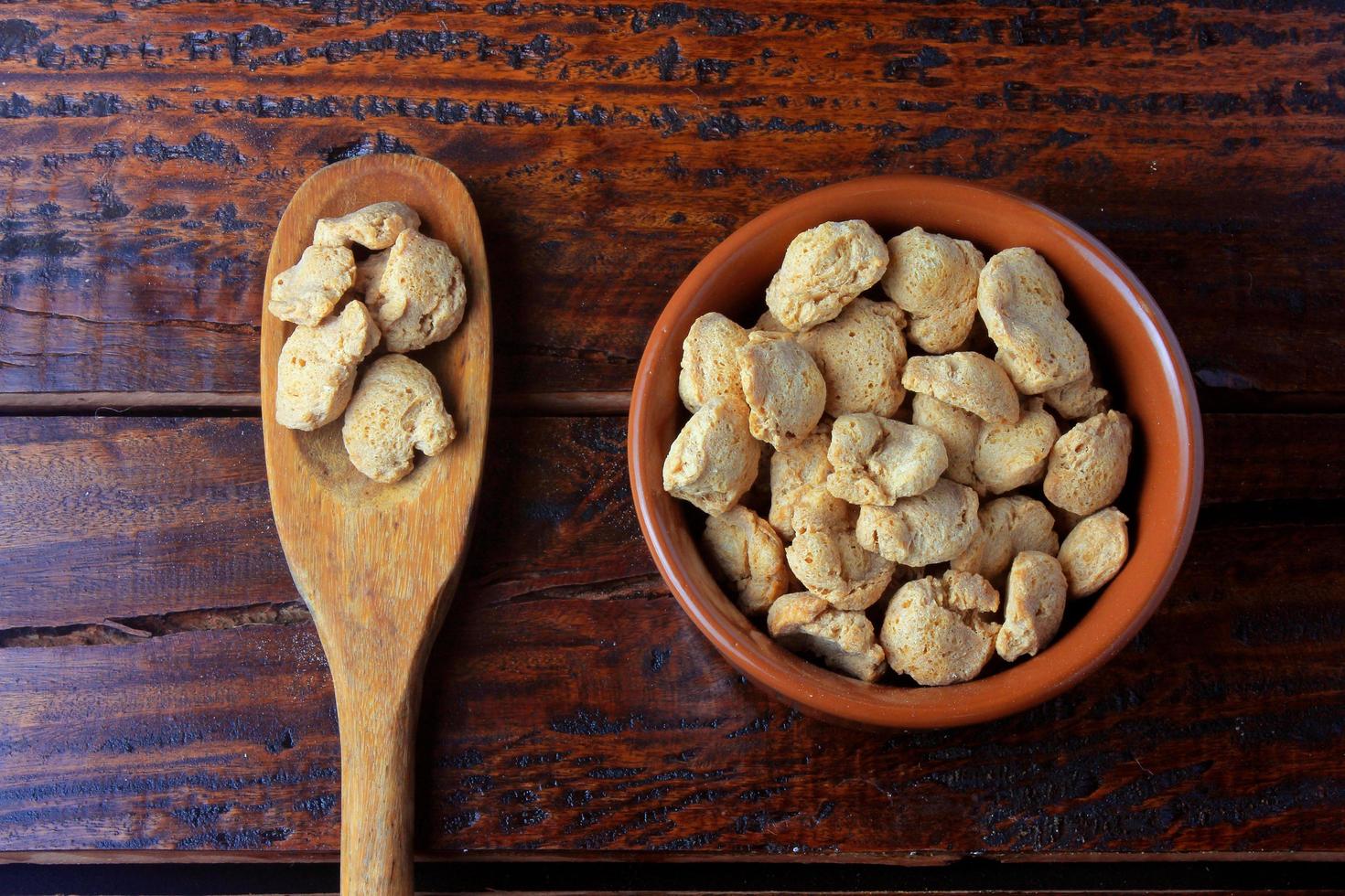 Soybeans meat, chunks in a brown ceramic bowl. Raw soybeans chunks on rustic wooden background photo