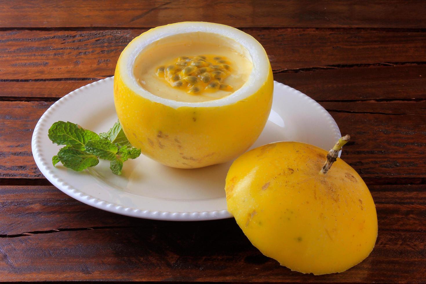 Postre mousse de maracuyá en la cáscara de la fruta, en la placa sobre la mesa de madera rústica foto