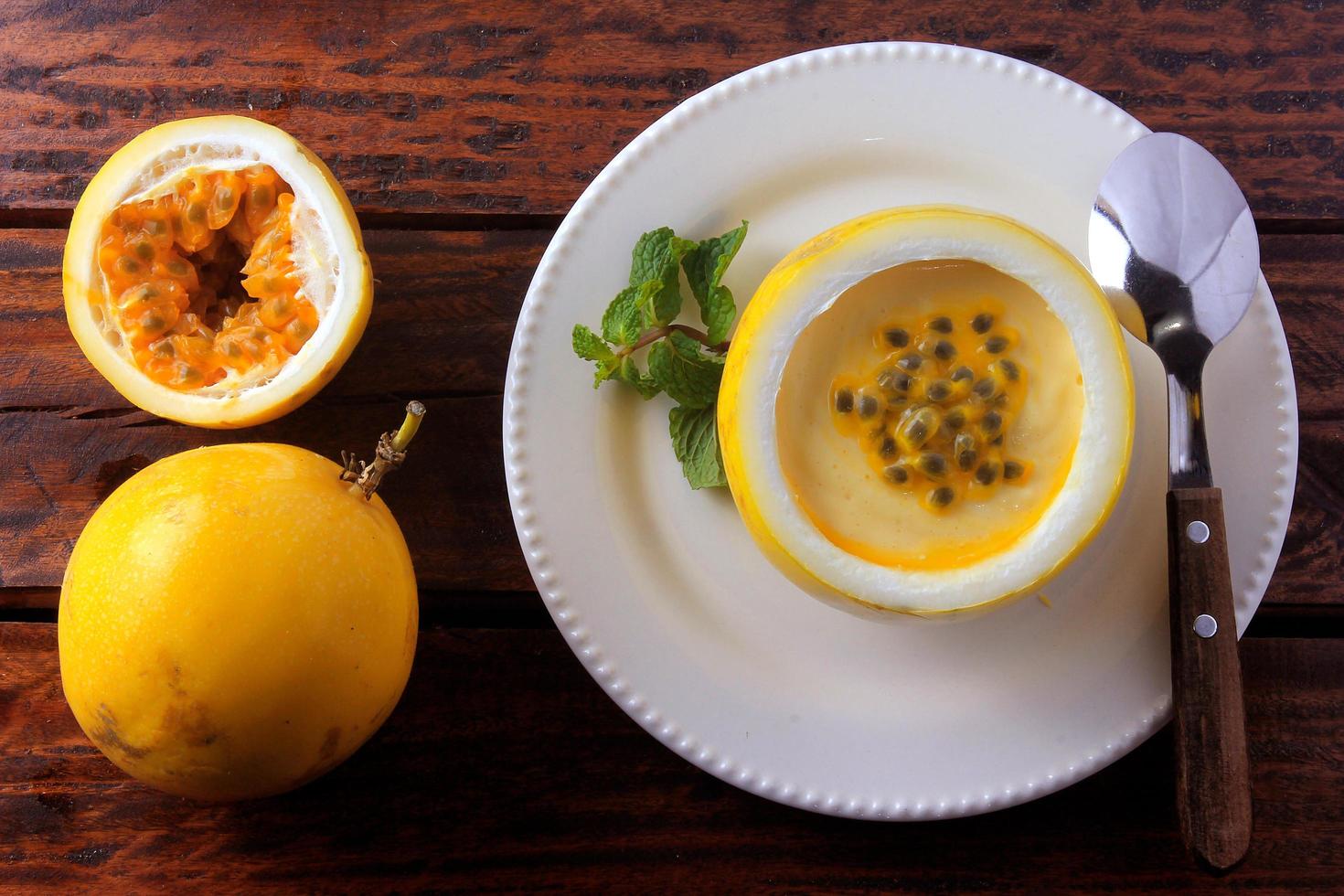 dessert Passion fruit mousse in the peel of the fruit, on plate over rustic wooden table photo