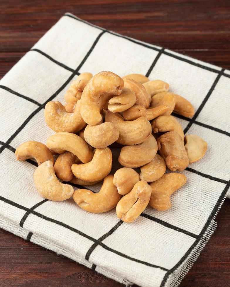 Cashew nuts in tablecloth on wooden table, Healthy snack, Vegetarian food photo