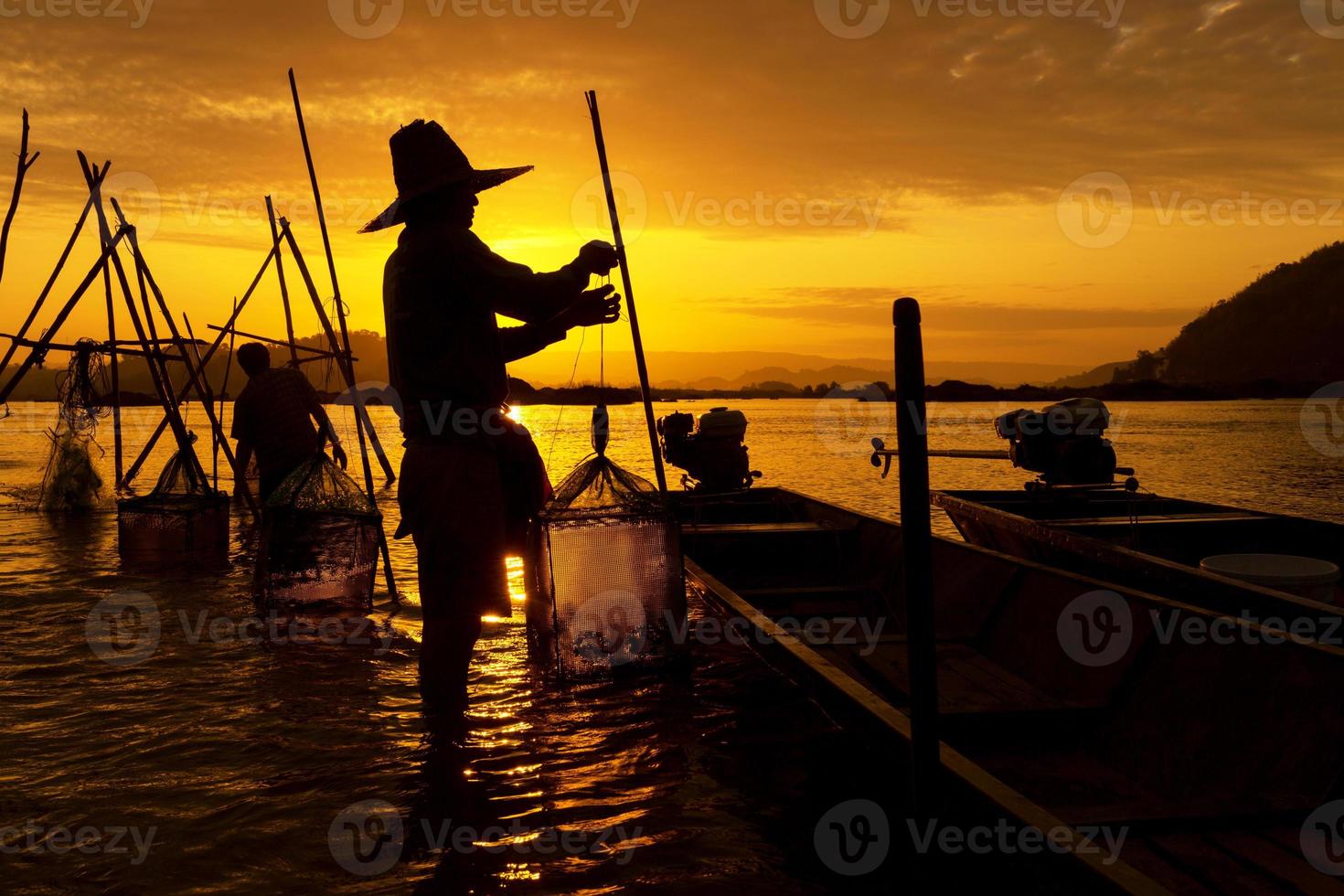 La silueta de los pescadores que trabajan en la hora dorada del amanecer en el río Mekong entre Tailandia y Laos foto