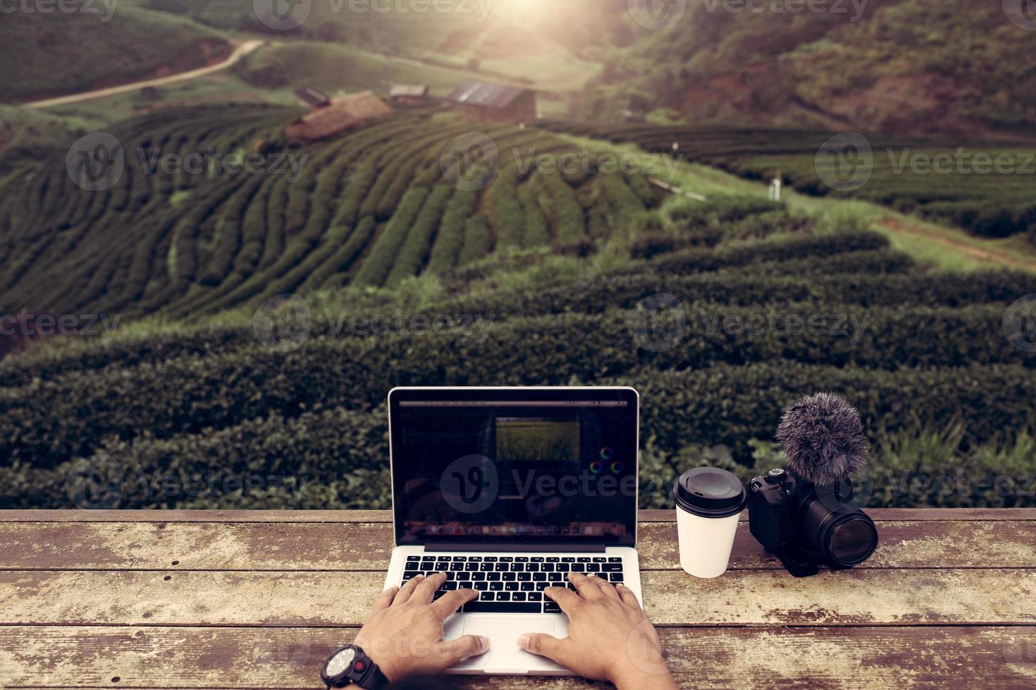 Top view creator or editor working use on laptop outdoor in green tea fields this is lifestyle of vlogger or blogger in Chiang Mai Thailand. photo