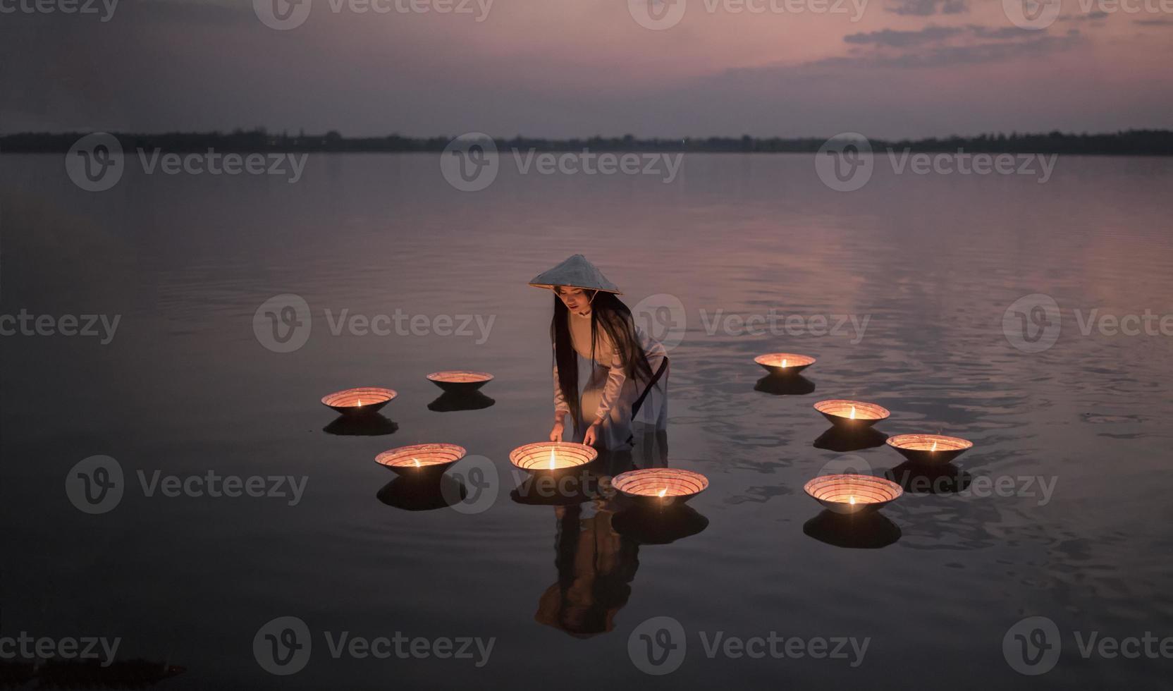 Pueblo vietnamita en ao dai vietnam traje tradicional en el lago atardecer con lámpara foto