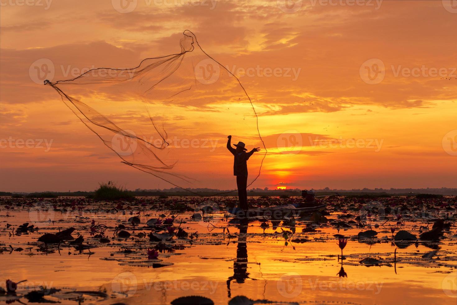 red de pesca de silueta este es un pescador de pie en un barco durante el amanecer en el lago udon thani, tailandia. foto