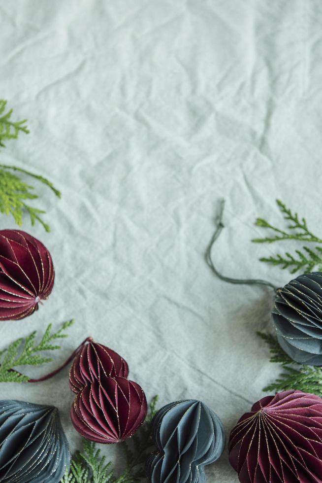 Ramitas de abeto con adornos de papel sobre el fondo textil arrugado de lino verde foto