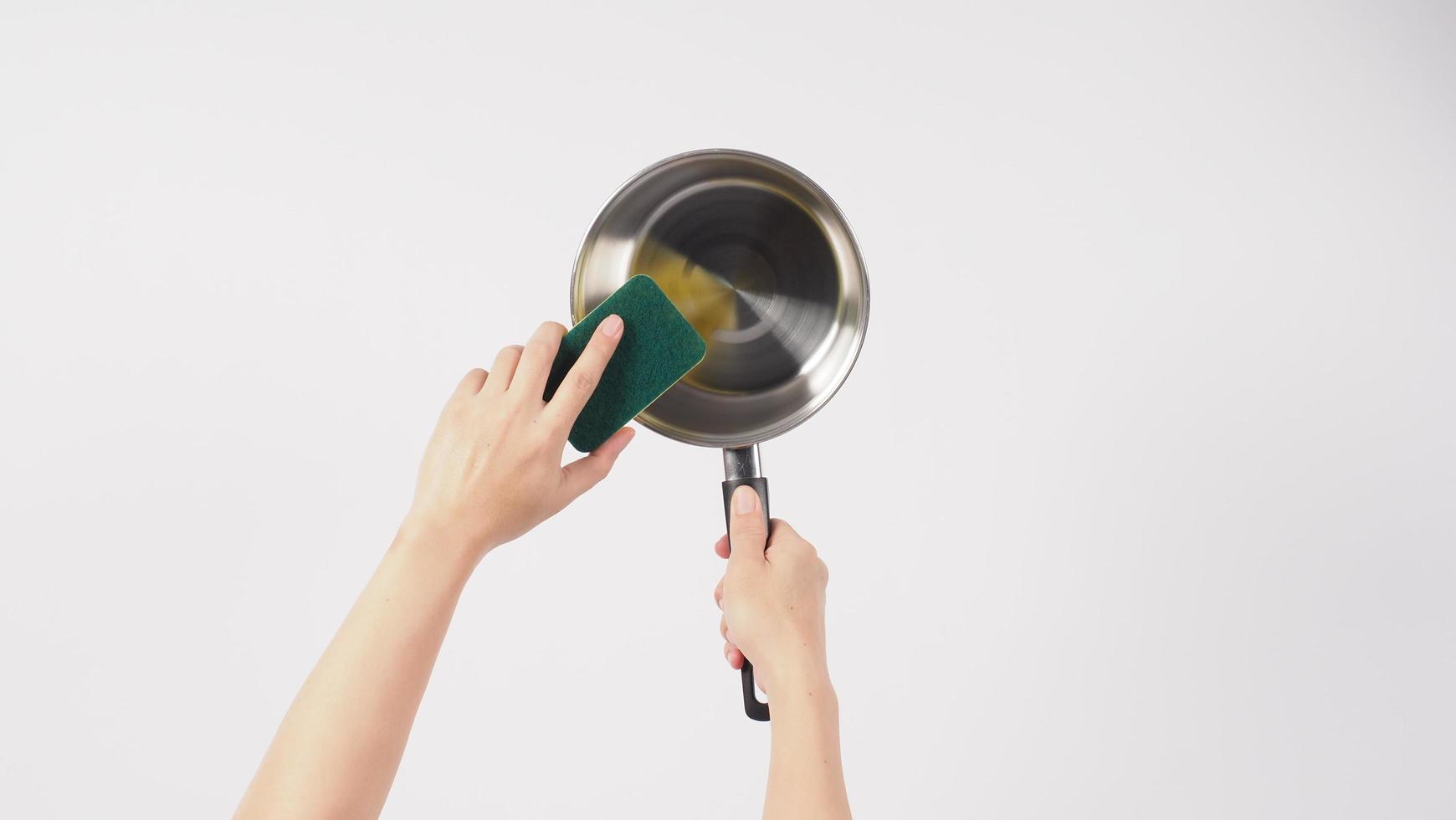 Pot cleaning. Man hand on white background cleaning the non stick pot photo