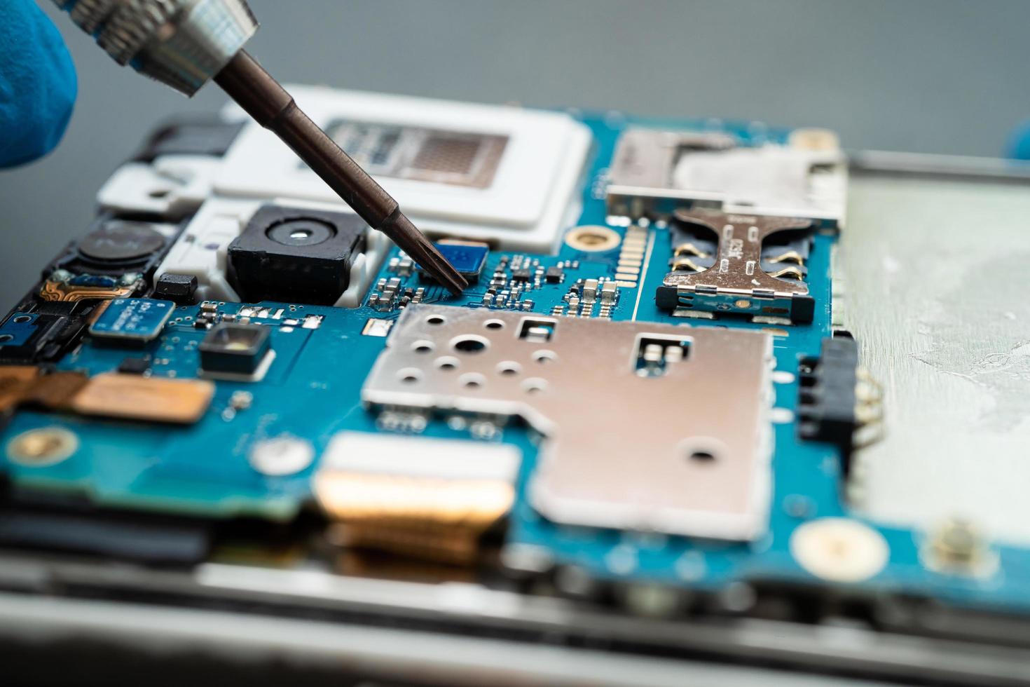 Technician repairing inside of mobile phone by soldering iron. Integrated Circuit. the concept of data, hardware, technology. photo