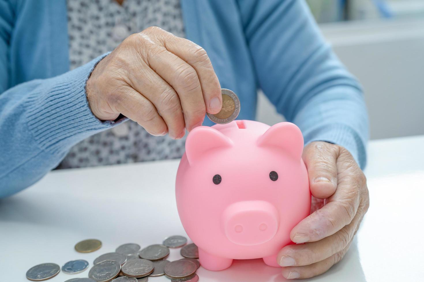 anciana asiática mayor o anciana mujer sosteniendo contando dinero de moneda en la hucha. pobreza, problema de ahorro en la jubilación. foto