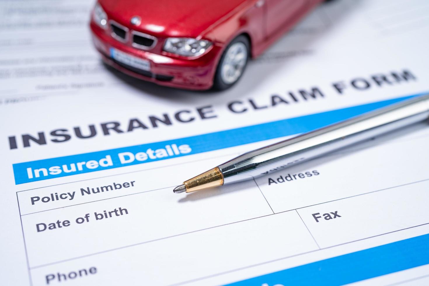 Pen with red car on Insurance  claim accident car form photo