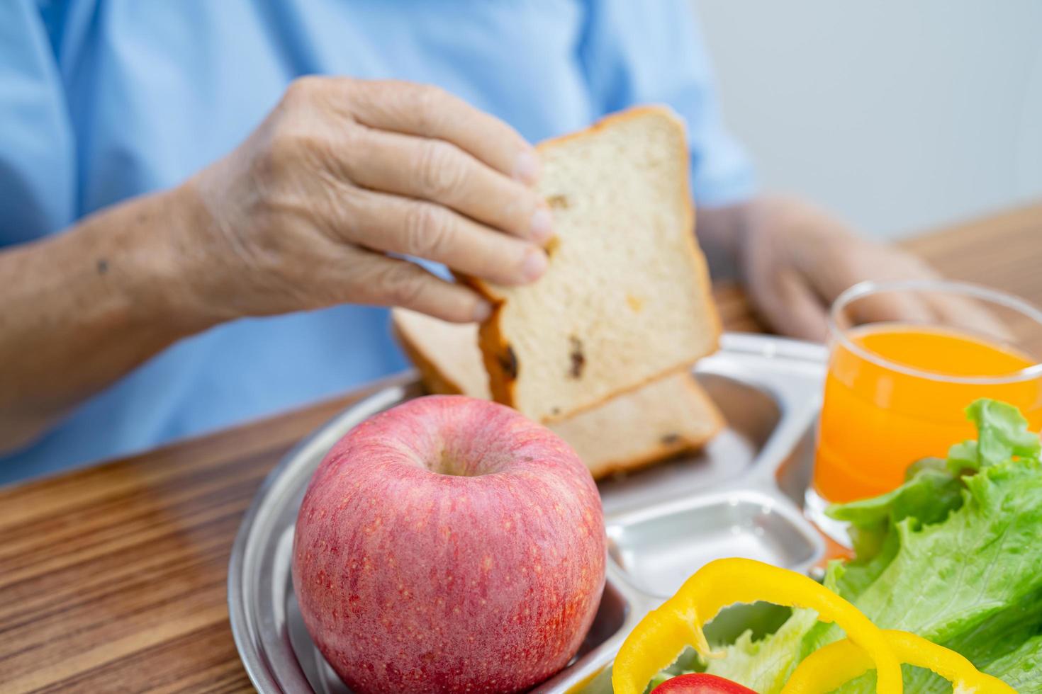 Asian senior or elderly old lady woman patient eating breakfast vegetable healthy food with hope and happy while sitting and hungry on bed in hospital. photo