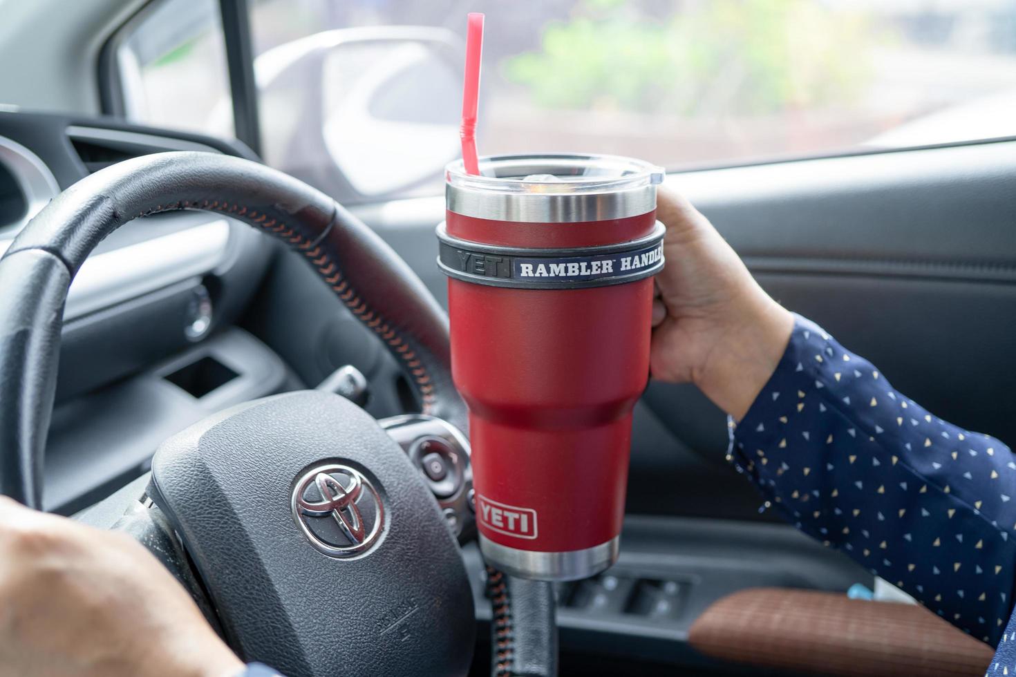 bangkok, tailandia, 1 de julio de 2021 dama asiática sosteniendo café helado en una taza de yeti en un automóvil toyota, peligrosa y con riesgo de accidente. foto