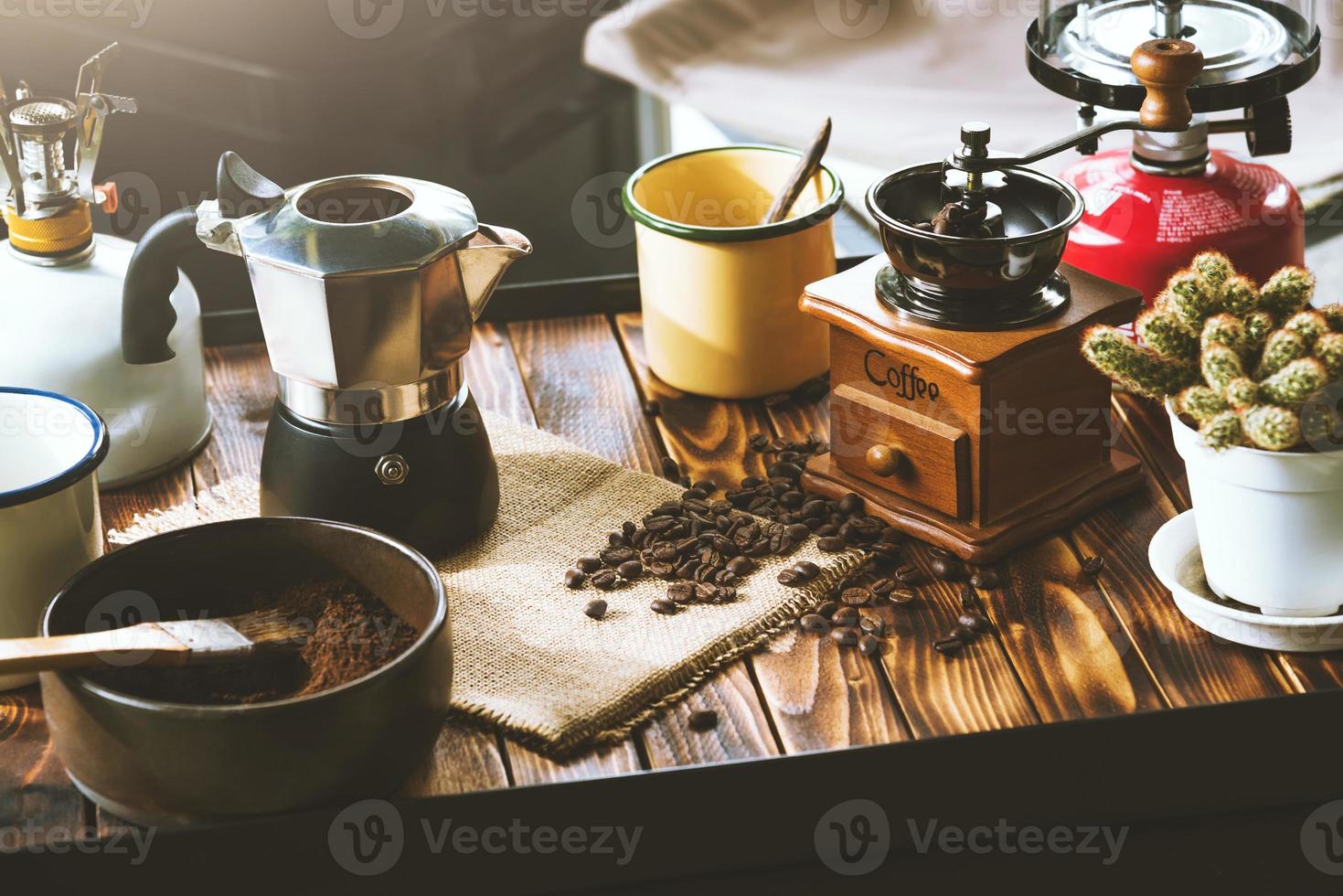 taza de café, granos tostados e ingredientes para hacer café y accesorios en el fondo de madera de la mesa. concepto de fabricación de café foto