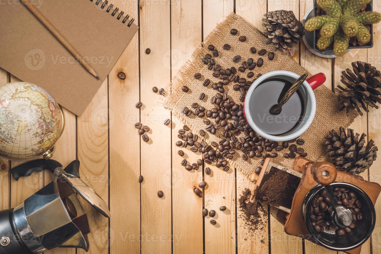 café negro y granos de café con molinillo de café, mapa del mundo sobre la mesa de madera foto