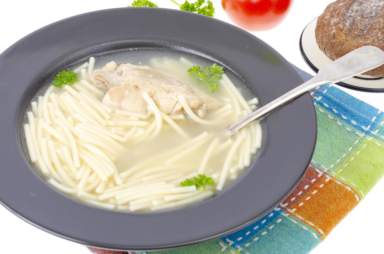 Chicken stock with slice of meat and noodles in black plate. photo