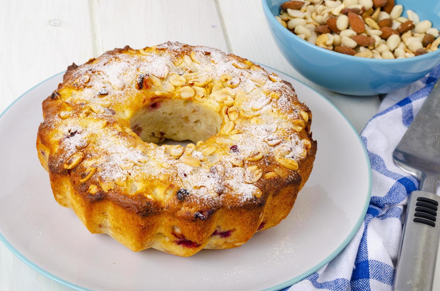 muffin casero dorado con nueces sobre mesa de madera blanca, servilleta. foto