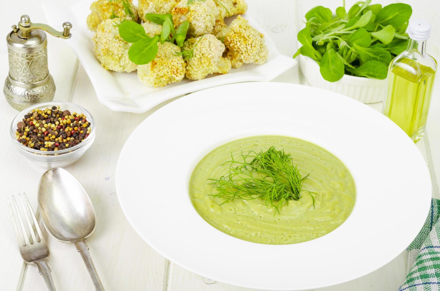 White plate with cream soup of green vegetables, healthy diet dish. photo