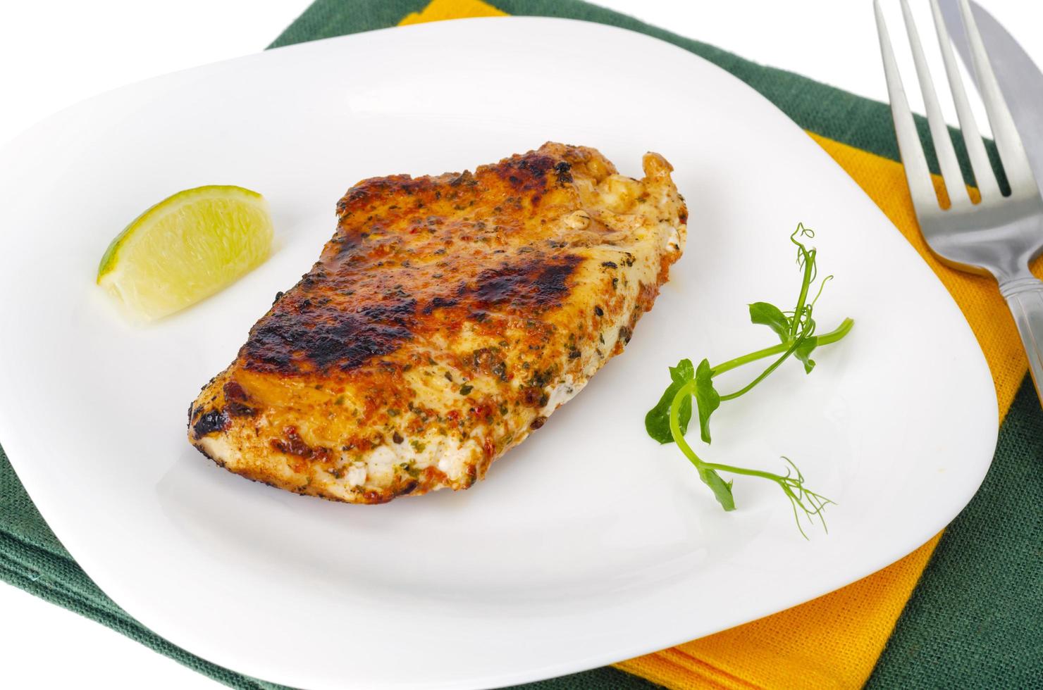 Piece of fried chicken with spices on white plate. photo