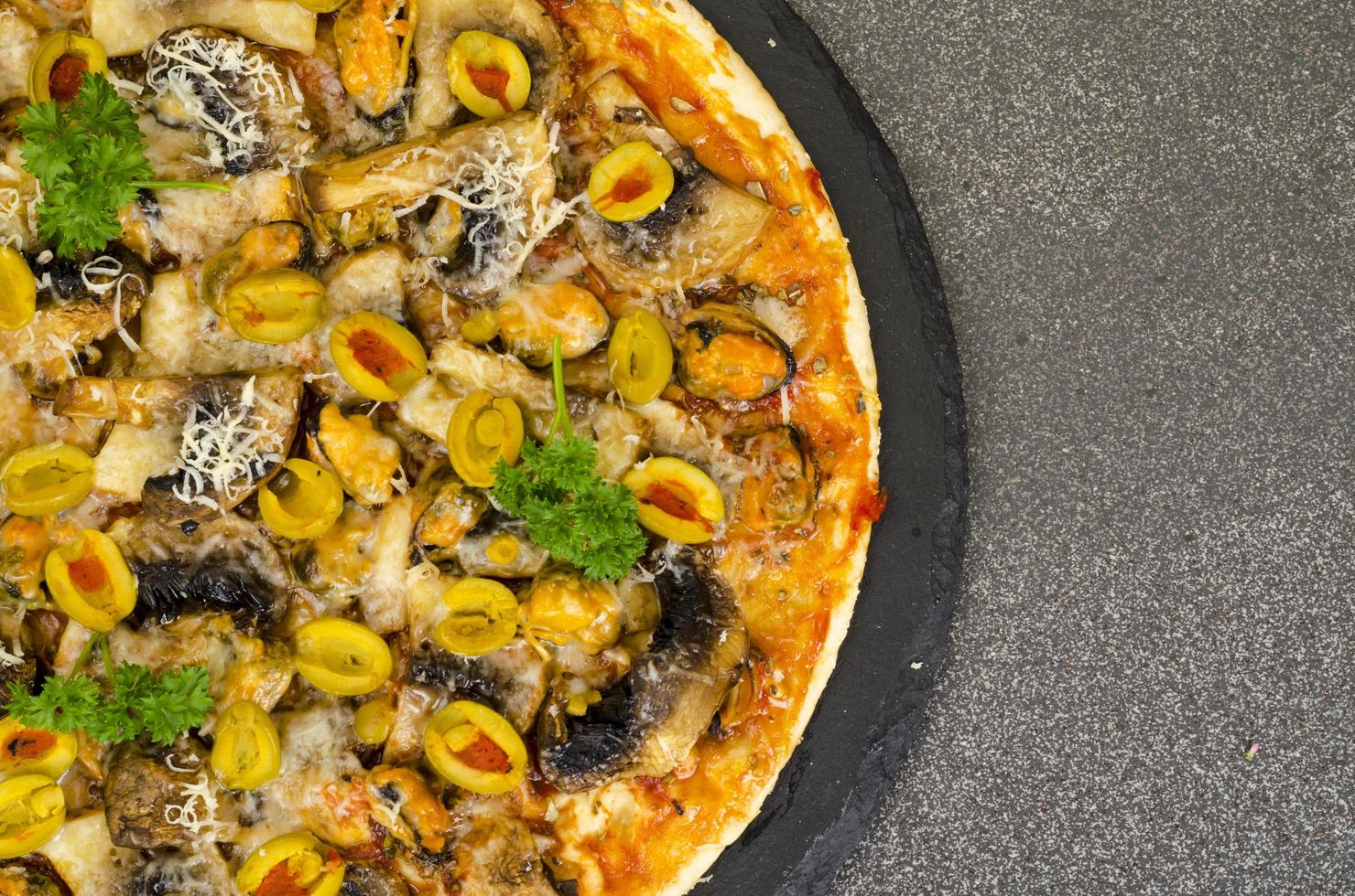 Pizza with mussels, mushrooms, green olives. Studio Photo
