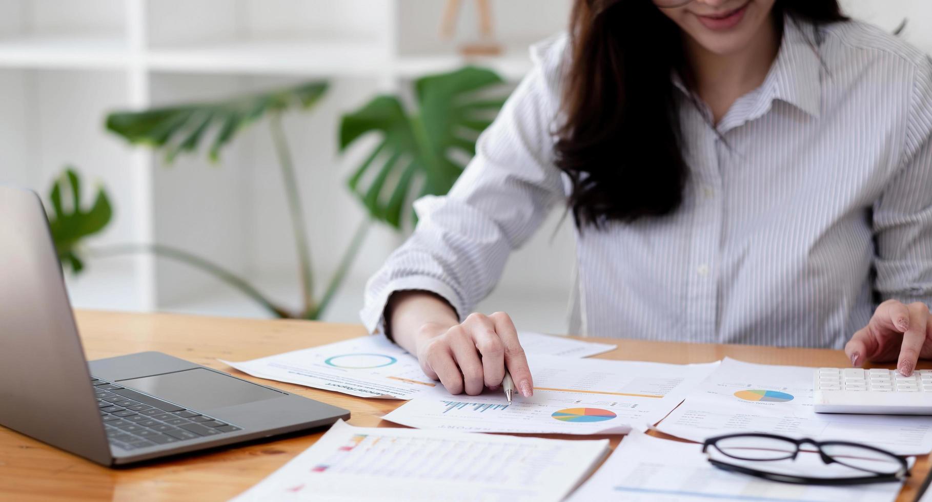 Portrait Asian Woman with financial report and calculator. Woman using calculator to calculate report at the table in office photo