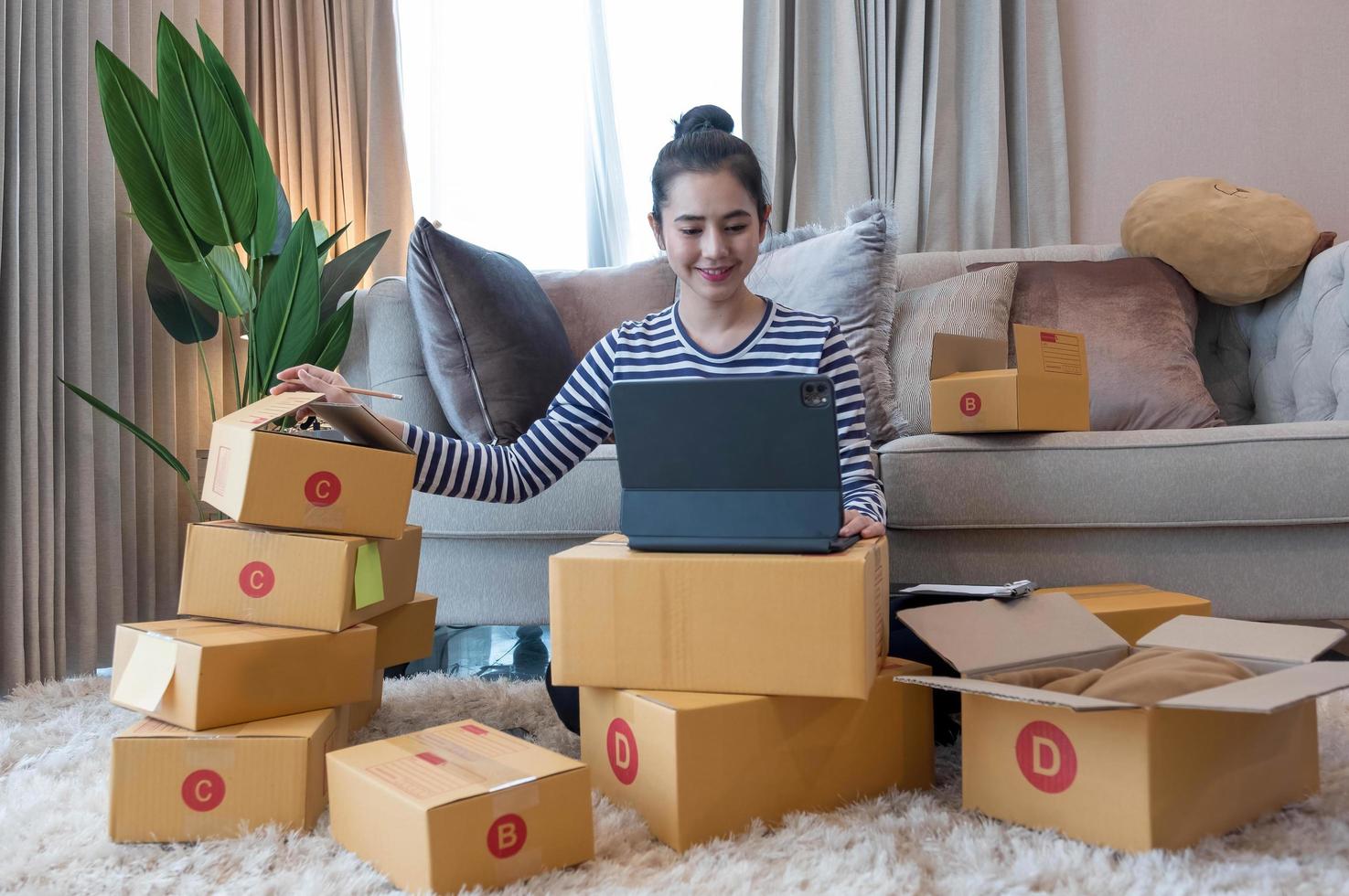 Online Marketing, Young start up small business owner writing address on cardboard box from list order. small business entrepreneur SME or freelance asian woman working with box at home photo